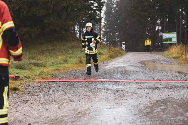 Teilnehmer in schwarzer Einsatzkleidung läuft auf die Zielmarkierung zu.