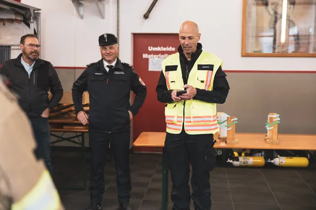 Organisator in Warnweste spricht neben einem uniformierten Feuerwehrmann.