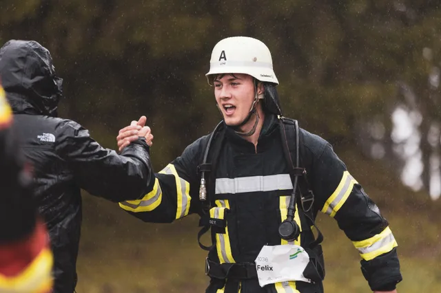 Teilnehmer mit weißem Helm klatscht im Ziel mit einem Zuschauer ab.