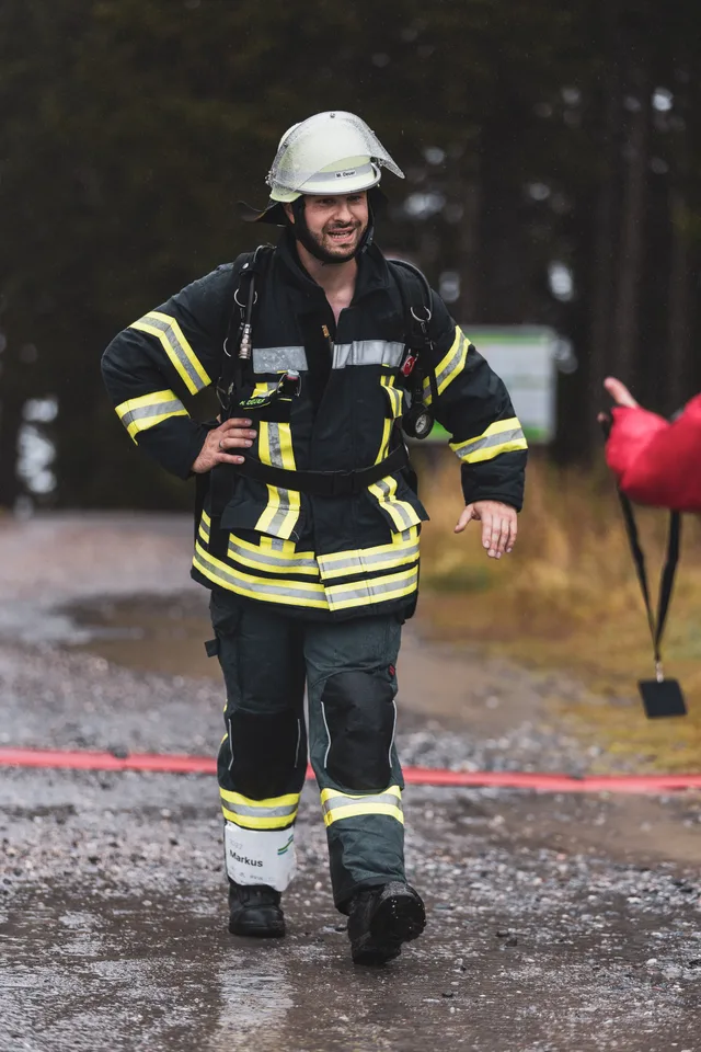 Lächelnder Teilnehmer in schwarzer Einsatzkleidung nähert sich dem Ziel.