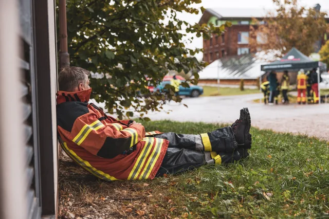 Teilnehmer in roter Einsatzkleidung sitzt mit ausgestrecktem Bein vor dem Hotel.