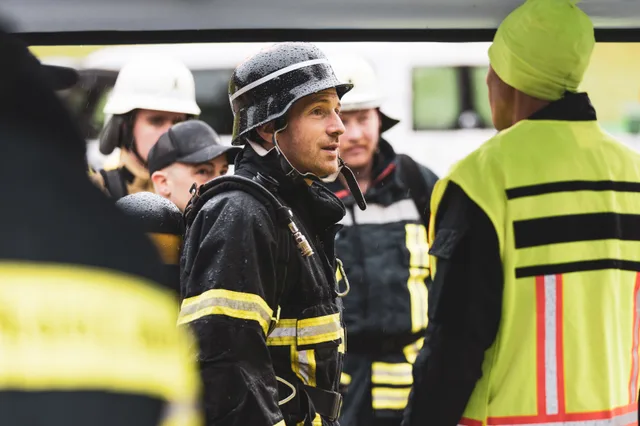 Teilnehmer mit schwarzem Helm im Gespräch mit einem Helfer in Warnweste.