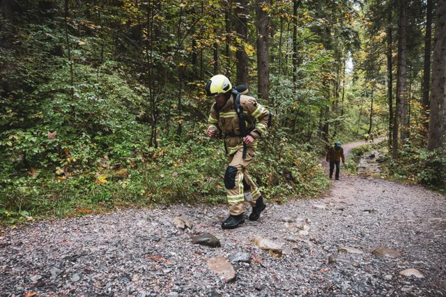 Teilnehmer in beiger Einsatzkleidung auf einem felsigen Waldweg.