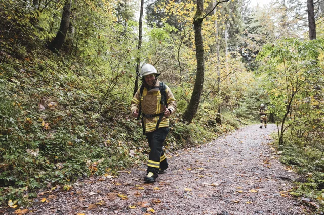 Teilnehmer mit weißem Helm und beiger Einsatzkleidung auf dem Waldweg.