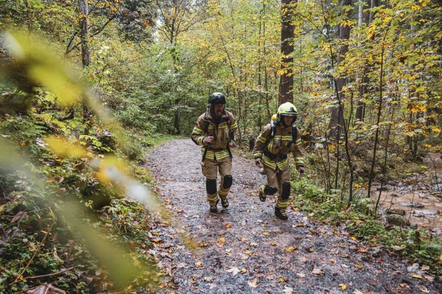 Zwei Teilnehmer in beiger Einsatzkleidung auf einem Waldweg.