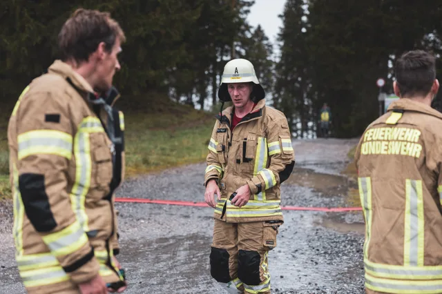 Teilnehmer in beiger Einsatzkleidung stehen mit abgelegter Ausrüstung im Zielbereich.