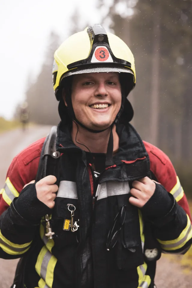 Lächelnde Teilnehmerin mit gelbem Helm hält beim Aufstieg die Tragegurte.